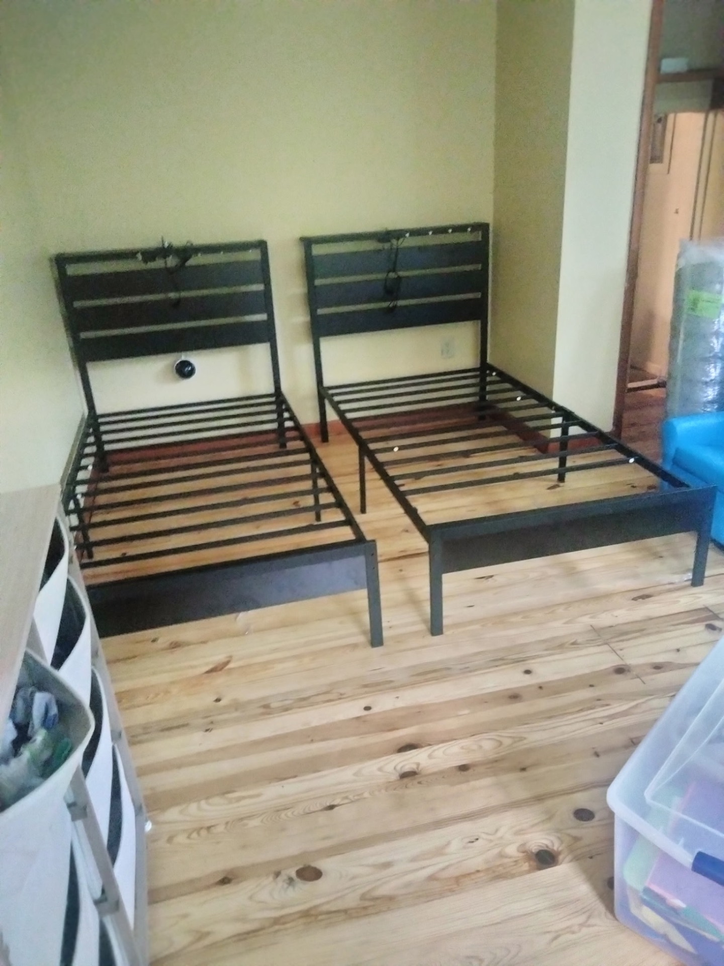 Two metal twin bed frames assembled side by side in a bedroom