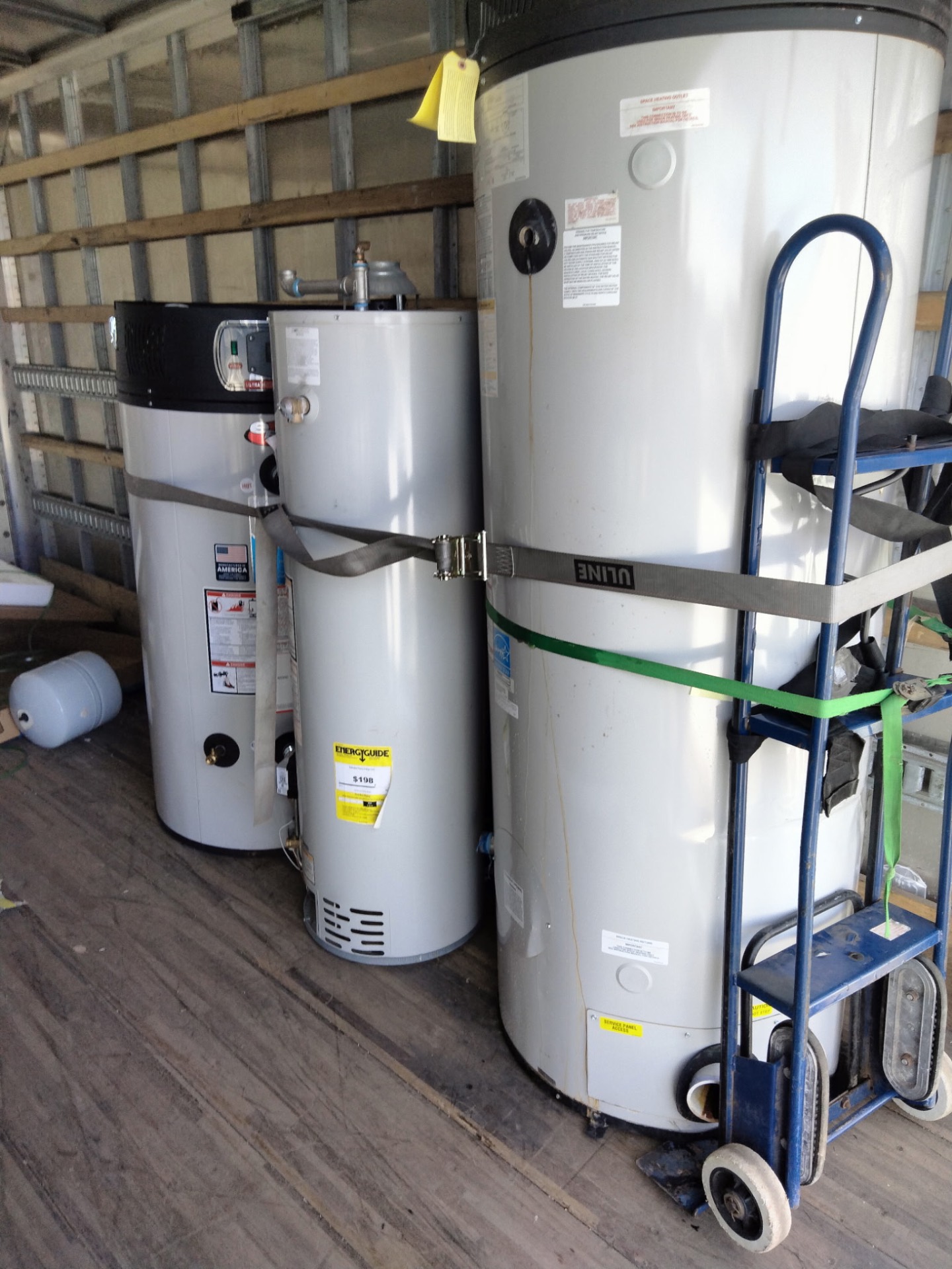 Three old water heaters loaded side by side in the moving truck for haul-away