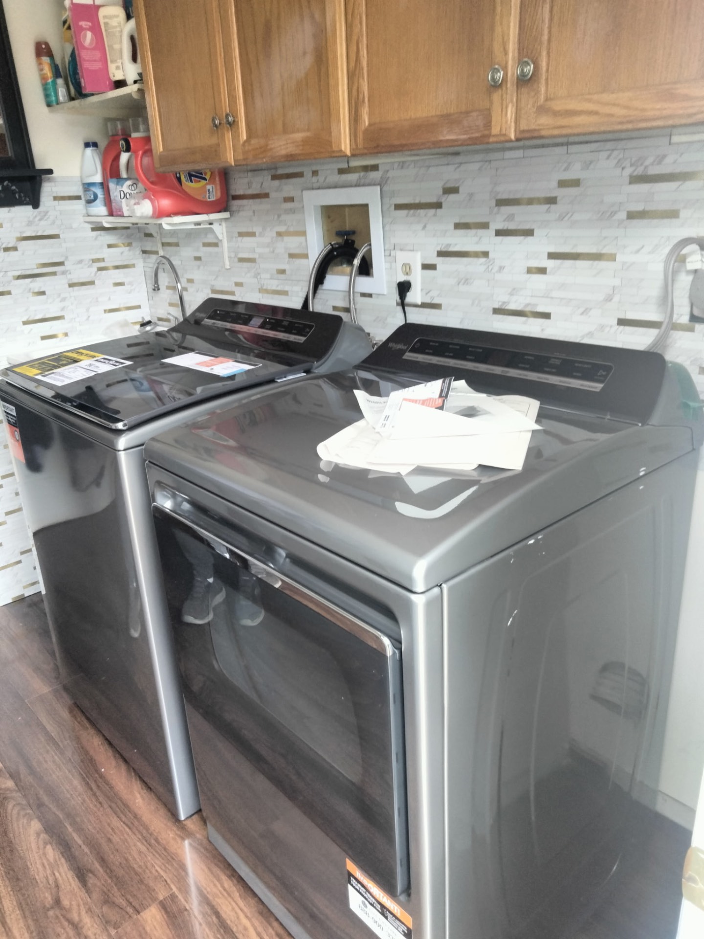 Matching graphite Whirlpool washer and dryer set placed side by side under laundry cabinets