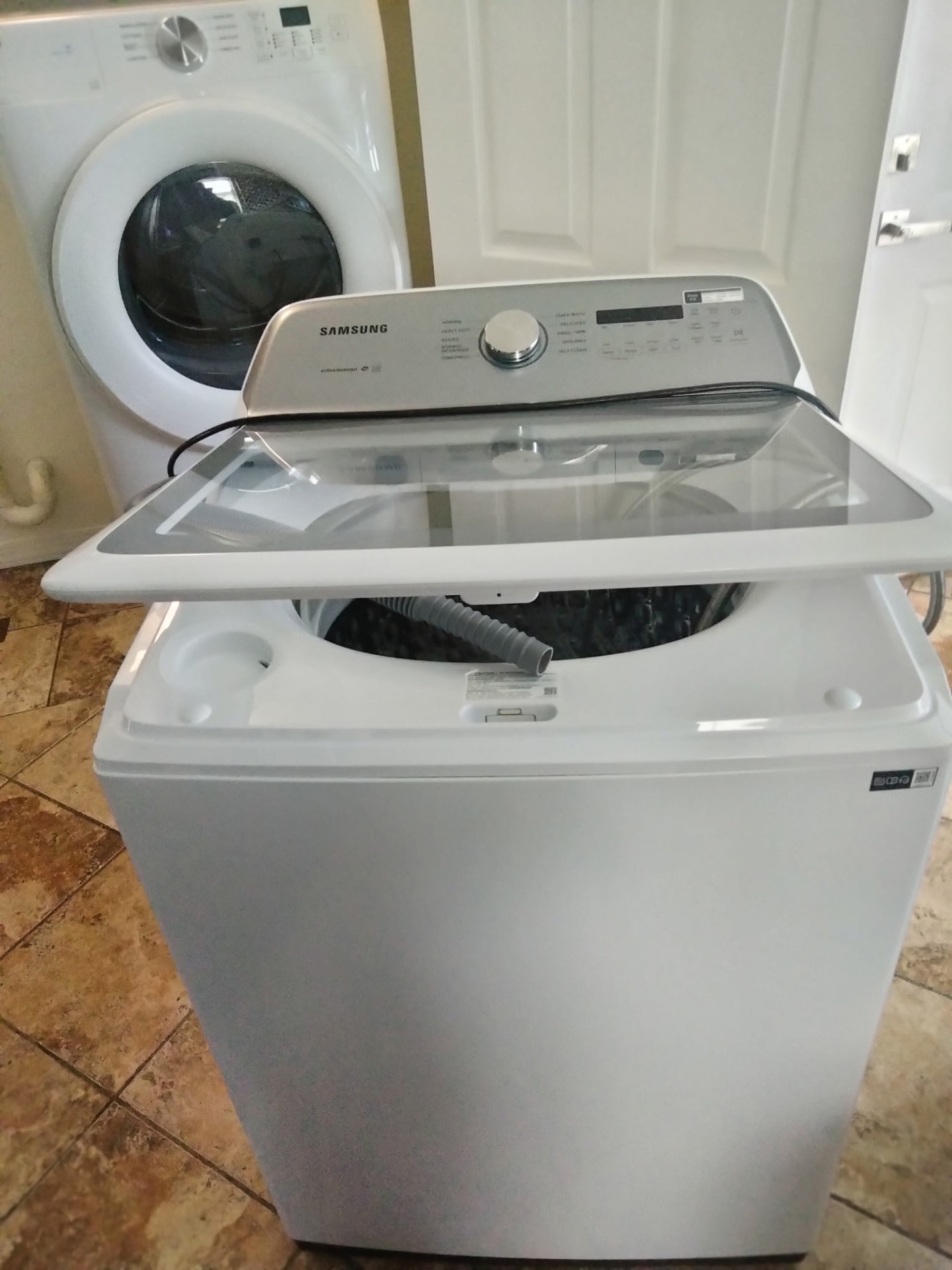 New white Samsung top-load washer delivered and positioned in a laundry room