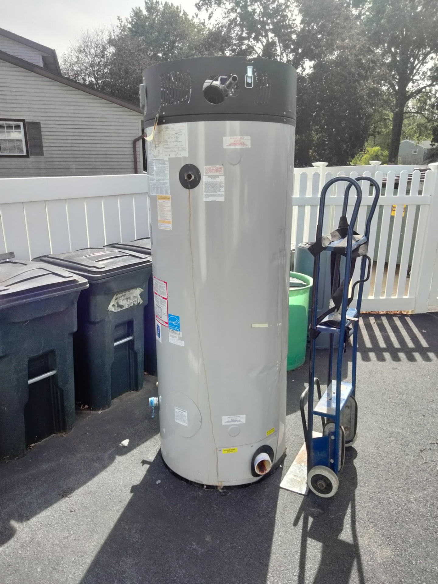 Large water heater standing outside beside a hand truck, ready for haul-away